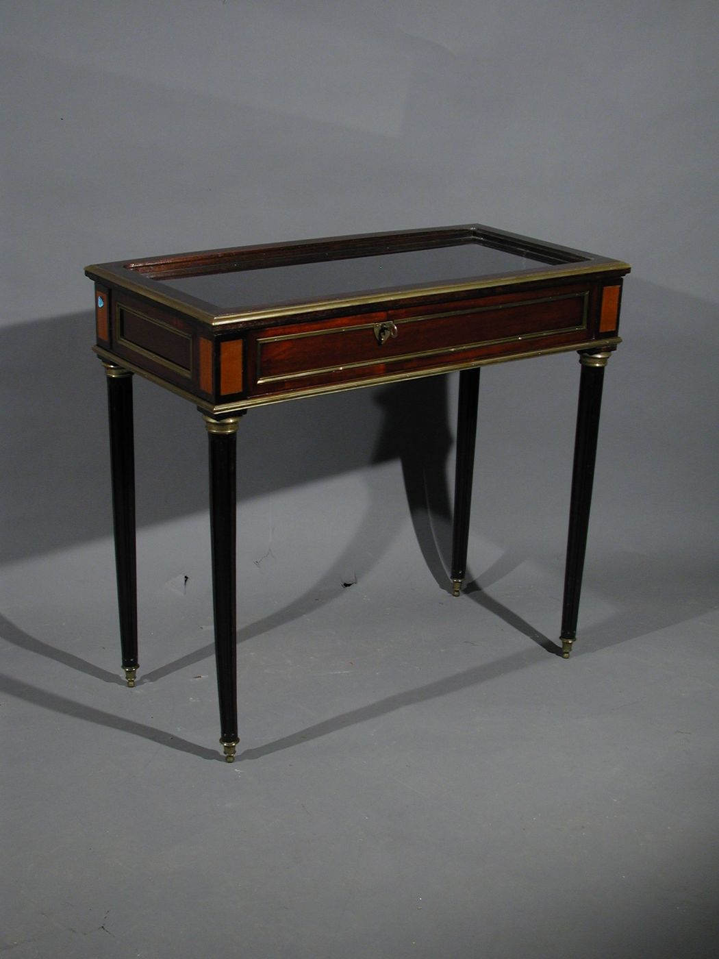 Tavolino a bacheca in mogano 4 gambe scanalate e con inserti in metallo.piano ribaltabile con interno a vetrina. Inghilterra XIX° sec.